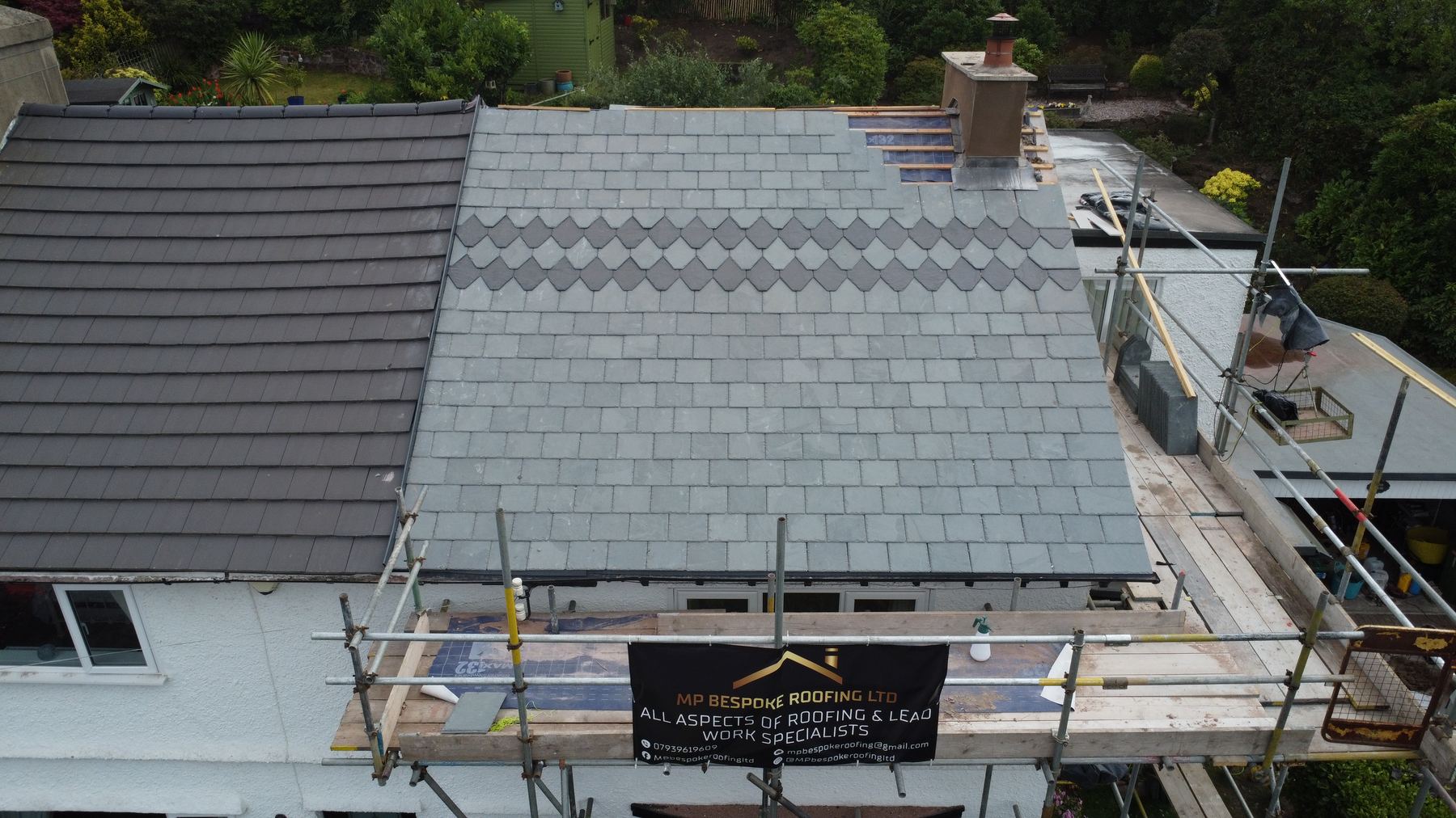 Roofing work in progress with scaffold and company banner